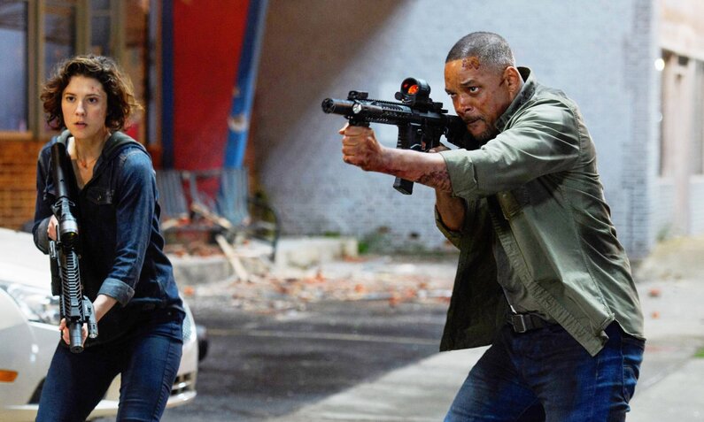 Mary Elizabeth Winstead und Will Smith gehen in einer Szene aus dem Film "Gemini" mit gezogenen Waffen eine Straße entlang. | © Imago Images/Everett Collection