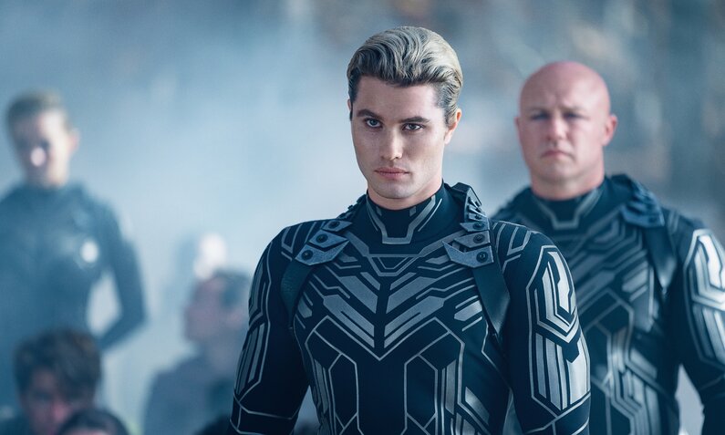 Chase Stokes als Persi und weitere Darsteller stehen in einer Szene aus dem Netflix-Film "Ugly - Verlier nicht dein Gesicht" in futuristischen Uniformen in einem Raum.  | © Netflix/Brian Douglas