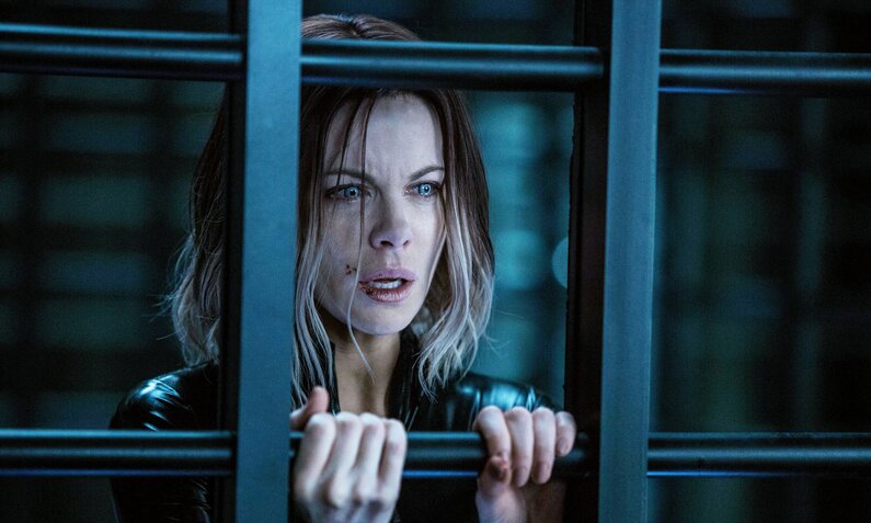 Nahaufnahme von Kate Beckinsale mit finsterem Blick hinter Gittern in einer Szene aus dem Kinofilm "Underworld: Blood Wars" | © ddp images/Screen Gems/courtesy Everett Collection