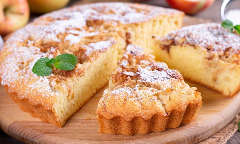 Angeschnittener Apfel-Joghurtkuchen mit Zimt und Puderzucker bestreut. | © Getty Images / 	Qwart