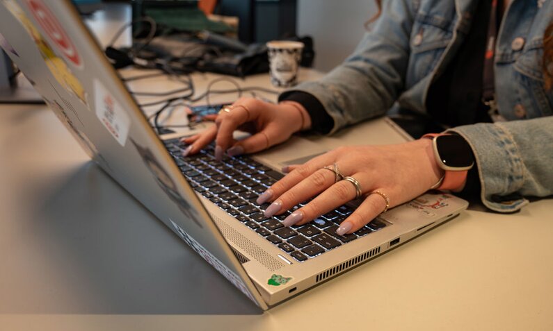 Eine Frau mit viel Schmuck an den Fingern nutzt ein Laptop, das mit vielen Aufklebern beklebt ist. | © Getty Images/Bloomberg