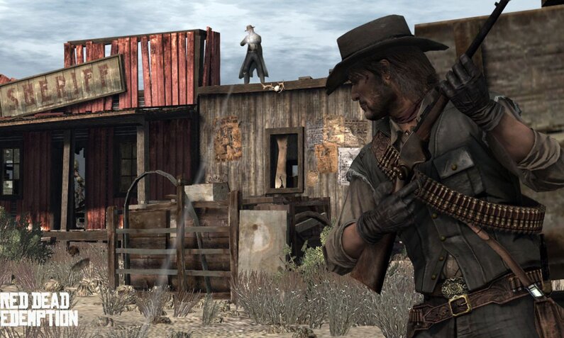 Westernheld John Marston hält ein Gewehr in der hand und bleibt in Deckung, während ein Mann von einem Dach, einige Meter entfernt, auf ihn schießt. | © Rockstar Games