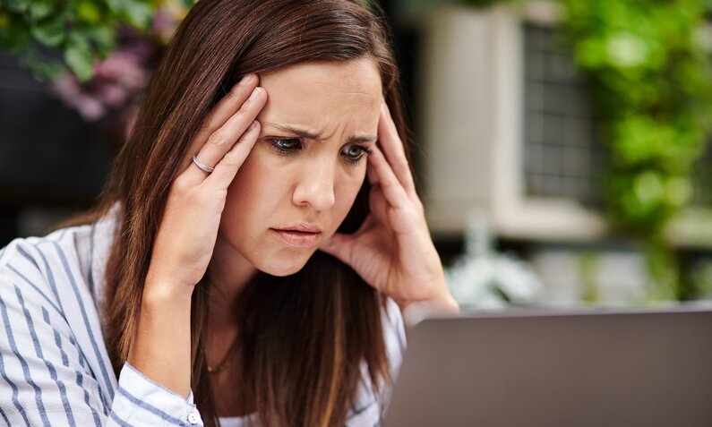 Junge Frau bllickt genervt auf ihren Computer-Bildschirm | © Getty Images/Dean Mitchell