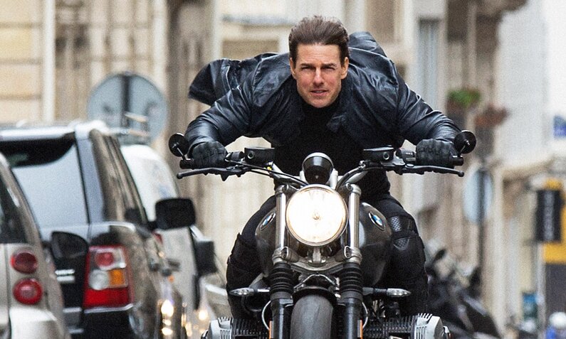 Tom Cruise als Ethan Hunt in voller Fahrt auf einem großen Motorrad in den Straßen von Paris im Kinofilm Szene aus dem Film "Mission impossible: Fallout" | © ddp images/Capital Pictures