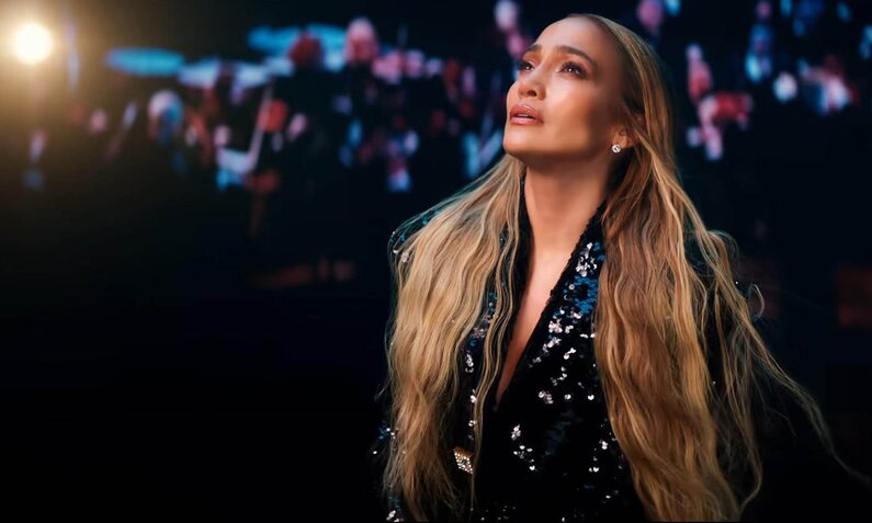 Jennifer Lopez steht mit langen, gewellten offenen Haaren in einem Pailettenanzug vor einem dunklen Hintergrund | © ddp images/Planet Photos