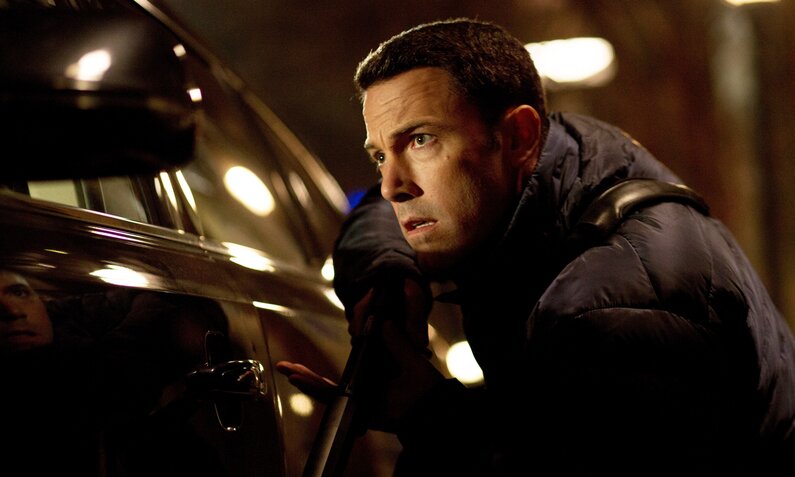 Ben Affleck kauert bei Nacht in einer Szene des Kinofilms "The Accountant" hinter einem Auto | ©  ddp images/Capital Pictures