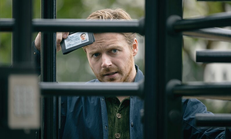 Jack Lowden blickt durch einen gesicherten Eingang und zeigt seinen Ausweis in einer Szene aus der Apple TV+ Serie "Slow Horses" | © Apple TV+