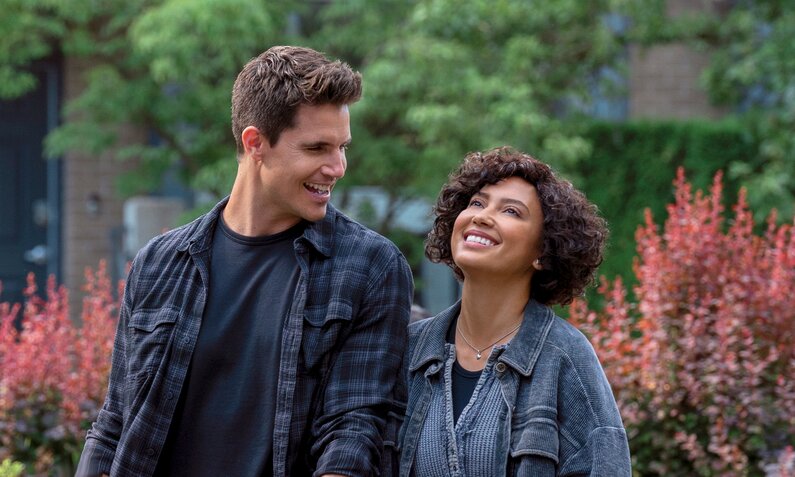 Robbie Amell und Andy Allo laufen Hand in Hand durch die Stadt in einer Szene aus der Serie "Upload" - im Hintergrund sind Blumen zu sehen. | © Amazon Prime Video