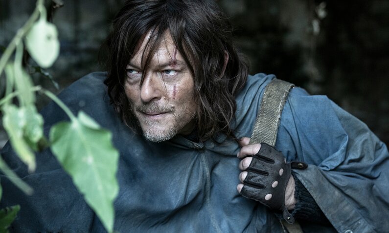 Nachaufnahme von Norman Reedus der unter Blättern hervorlugt in einer Szene der Serie "The Walking Dead: Daryl Dixon" | © MagentaTV/AMC