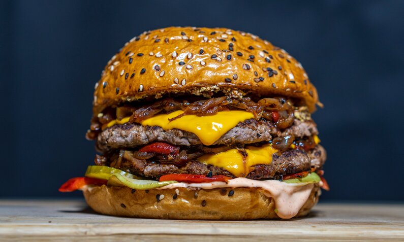 Burger in Nahaufnahme vor dunkelblauem Hintergrund und doppelt belegt mit Beef. | © Getty Images / novanym 95 / 500px