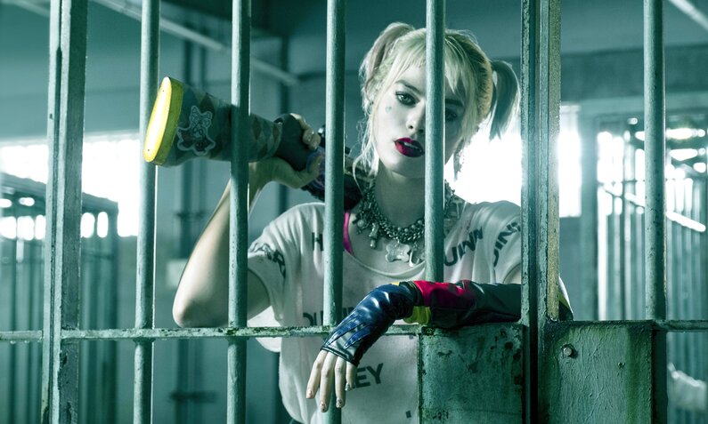 Margot Robbie als Harley Quinn hinter Gittern mit einem Gewehr über der Schulter in einer Szene aus dem Kinofilm "Birds of Prey: And the Fantabulous Emancipation of One Harley Quinn" | © ddp images/LMKMEDIA