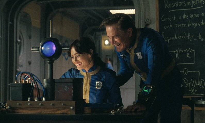 Ella Purnell und Kyle MacLachlan in Uniformen an einem Arbeitstisch in einem Bunker in einer Szene aus der Prime Video Serie "Fallout" | © Amazon Content Services LLC