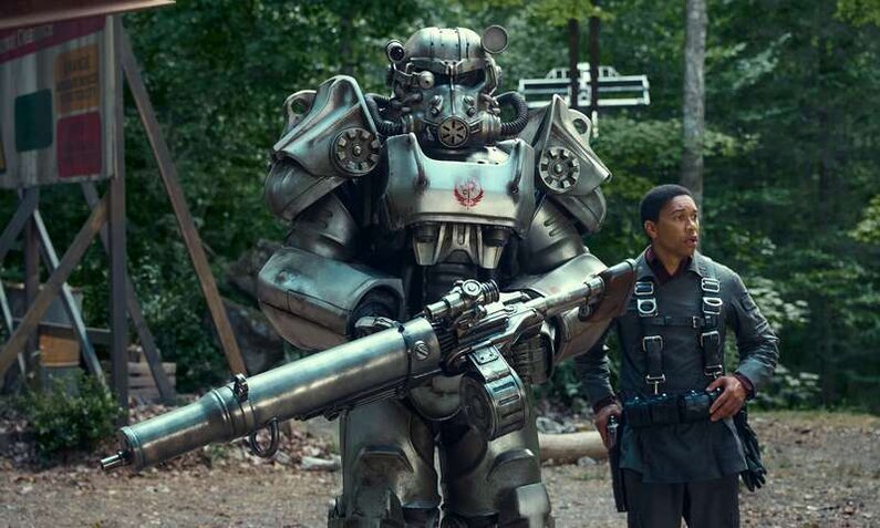 Aaron Moten als Soldat Maximus steht neben einem riesigen Roboter im Wald in einer Szene aus der Prime Video Serie "Fallout". | © Amazon Content Services LLC