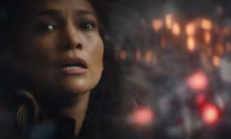 Nahaufnahme des erschrockenen Gesichts von Jennifer Lopez in einem Screenshot aus dem Trailer zum Netflix-Film "Atlas". Rechts von ihr ist eine Explosion zu sehen. | © Screenshot Trailer YouTube @Netflix