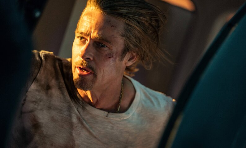 Nahaufnahme von Brad Pitt in dramatischem Licht an Bord eines Hochgeschwindigkeitszuges in einer Szene aus dem Kinofilm "Bullet Train" | © Imago Images/Scott Garfield/Sony Pictures