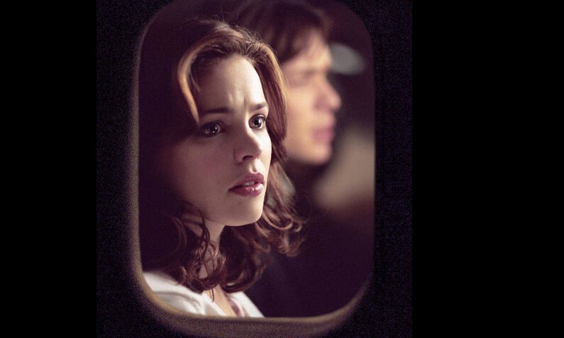 Blick von außerhalb eines Flugzeugs bei Nacht durchs Fenster auf das Gesicht von Rachel McAdams, im Hintergrund ist verschwommen Cillian Murphy als Sitznachbar zu sehen in einer Szene aus dem Film "Red Eye". | © Imago Images/EntertainmentPictures