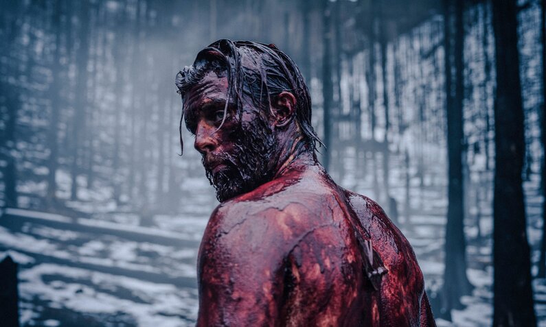 Jannis Niewöhner als Siegfried von Xanten mit blutbedecktem Oberkörper in einem Winterwald in der RTL+ Serie "Hagen" | © RTL/Constantin Film/Stanislav Honzík