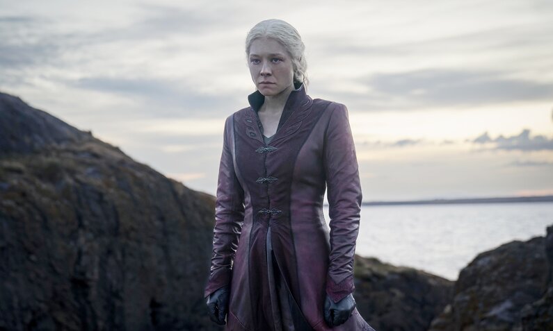 Emma D'Arcy steht im mittelalterlichen Gewand mit grimmigem Gesicht an einem Strand in einer Szene aus der HBO-Serie "House of the Dragon". | ©  2023 Home Box Office, Inc. All rights reserved.