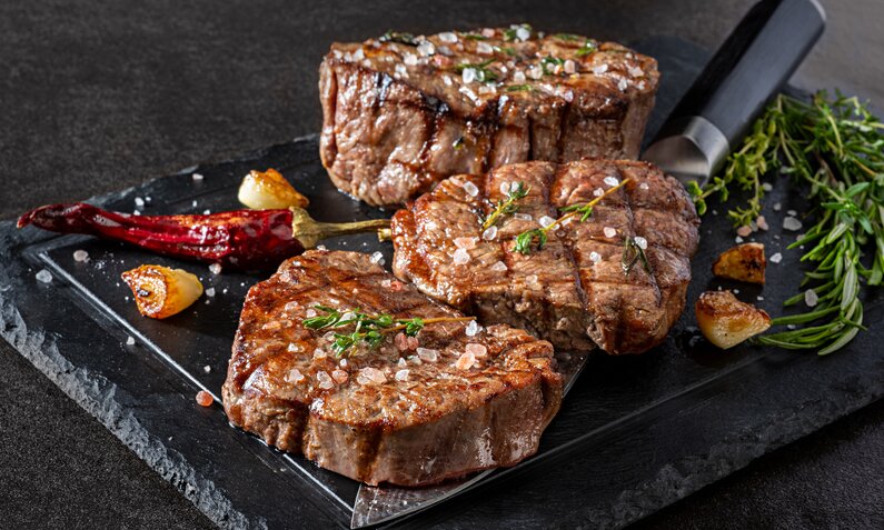 Gegrilltes Fleisch in Marinade auf einem Teller, daneben frische Chili und Salz. | © Getty Images / BURCU ATALAY TANKUT