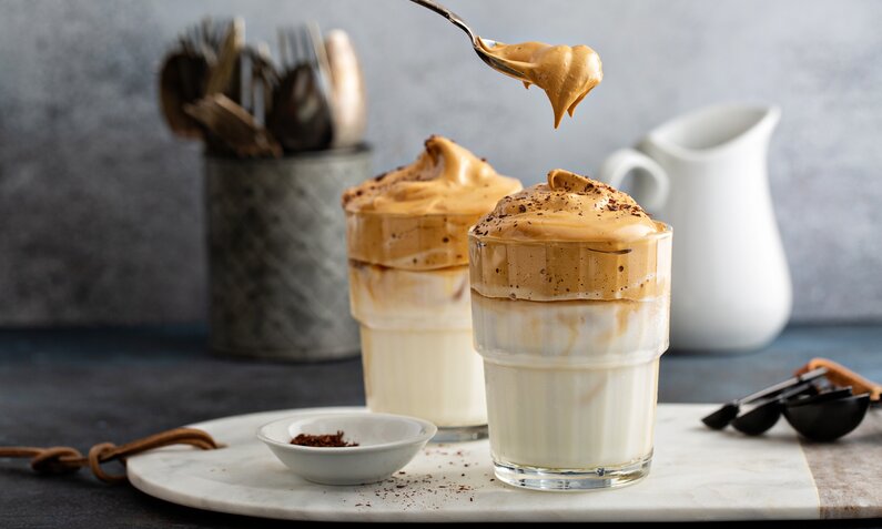 Kaffeedessert mit Mascarpone in zwei Dessertgläsern, daneben frische Kaffeebohnen. | © Adobe Stock / fahrwasser