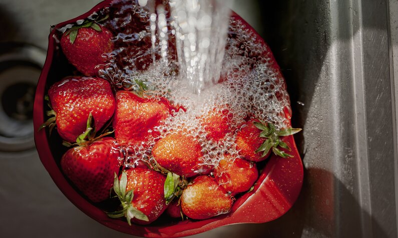 Erdbeeren werden von Händen in einem Waschbecken mit kaltem abgespült. | © Getty Images / devonanne