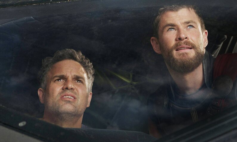Mark Ruffalo und Chris Hemsworth blicken beide mit ernsten Gesichtern aus einem Fenster in einer Szene des Kinofilms "Thor: Ragnarok" | © Imago Images/Everett Collection