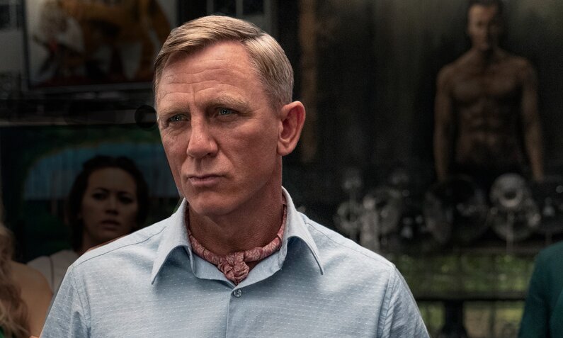 Nahaufnahme von Daniel Craig als Detektiv Benoit Blanc mit ernstem Gesicht in einer Szene aus dem Netflix Film "Glass Onion: A Netflix Mystery" | © Imago Images/Everett Collection