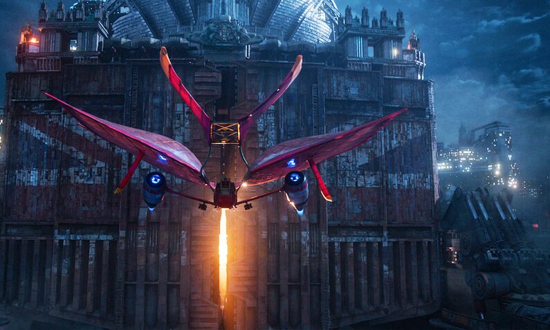 Ein futuristisches rotes Flugobjekt vor einer mächtigen Festung in einer Szene aus dem Kinofilm "Mortal Engines - Krieg der Städte" | © Imago Images/Cinema Publishers Collection