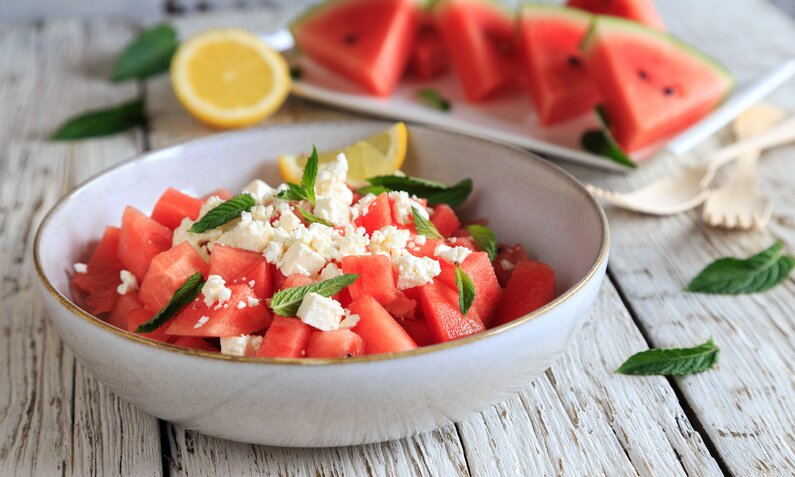 Wassermelone in Stücken angerichtet in Schale mit zerbröselten Feta und einigen Minzeblättern. | © Getty Images / juefraphoto