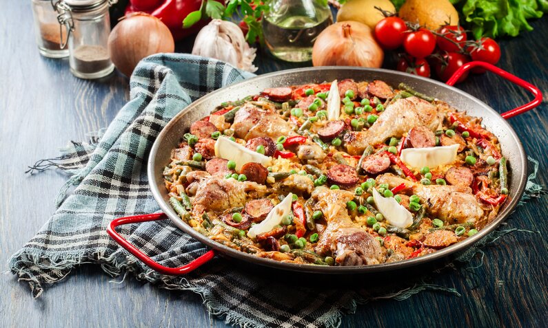 Hähnchen-Paprika-Pfanne angerichtet in einem Wok, darauf frische Limettenspalten. | © Getty Images / fotek