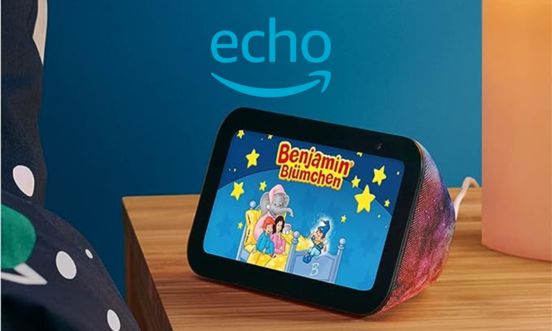 Auf einem Echo-Show-Kids-Bildschirm auf einem Tisch wird eine Benjamin Blümchen-Geschichte gezeigt, daneben eine bunte Bettdecke | © Amazon