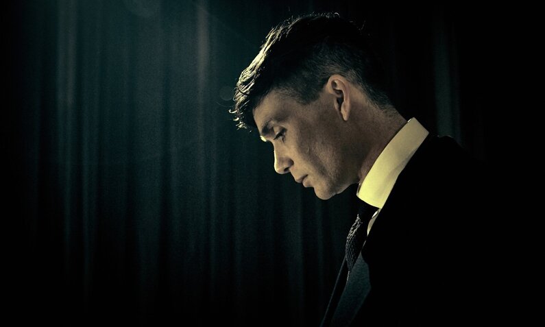 Cillian Murphy als Clanchef Thomas Shelby senkt nachdenklich den Kopf in einem dunklen Raum in einer Szene aus der Gangsterserie "Peaky Blinders" | © Tiger Aspect, Caryn Mandabach Productions Ltd. 2017