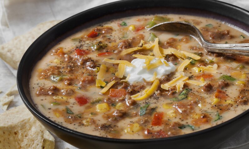 Suppe mit Hackfleisch, Paprika und Mais in einem Suppenteller angerichtet mit Löffel. | © Getty Images / 	LauriPatterson