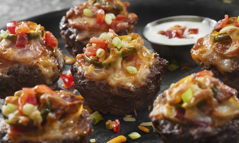 Mini-Burger auf Backblech in Nahaufnahme daneben roter Dip in Schale. | © Getty Images / 	LauriPatterson