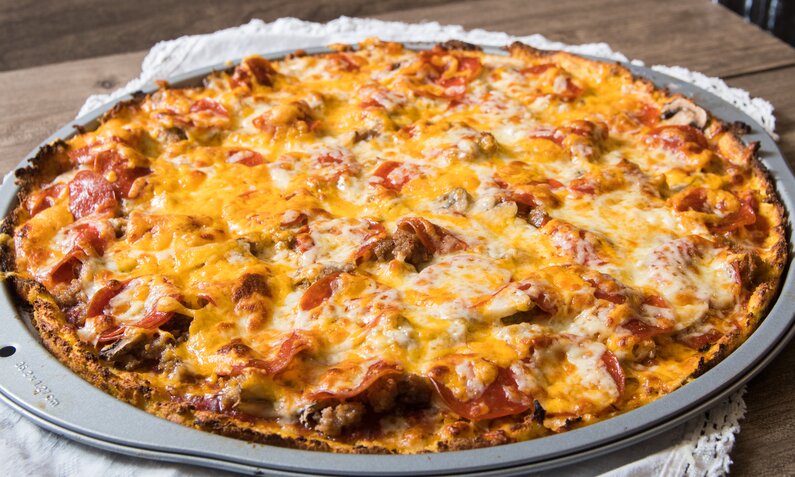 Schüttelpizza ohne Mehl in Nahaufnahme auf Backblech, auf Holztisch stehend. | © Adobe Stock / nsc_photography