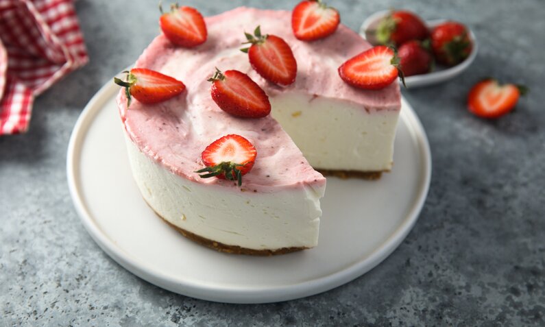 Saftiger Joghurt-Kuchen mit frischen Erdbeeren ohne Mehl, angerichtet auf Kuchenteller. | © Getty Images / Mariha-kitchen