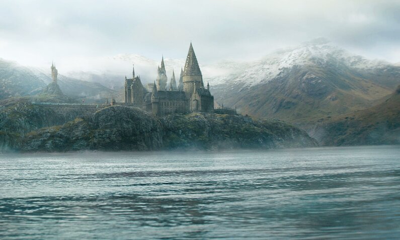 Malerische Landschaft mit See und Schluss und Bergen im Hintergrund in einer Szene aus dem Kinofilm "Phantastische Tierwesen: Dumbledores Geheimnisse" | © Imago Images/Picturelux/Warner Bros.