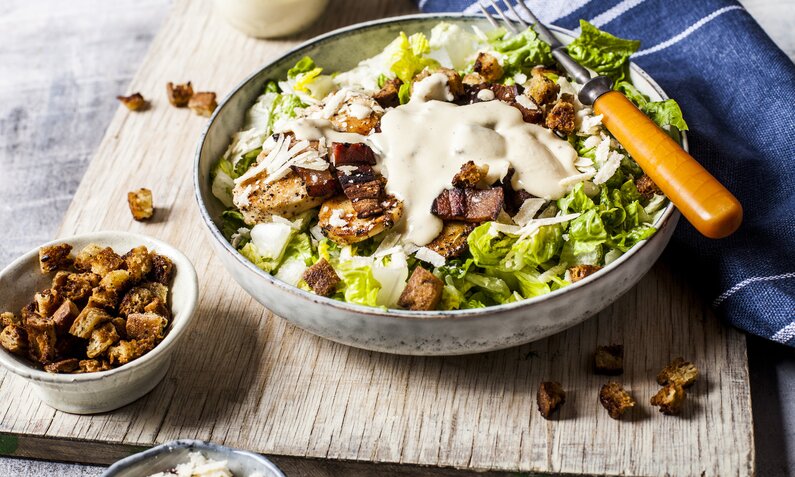 Caesar Salat mit Joghurt-Dressing in einer Schale angerichtet, darauf Croutons. | © Getty Images / 	Westend61