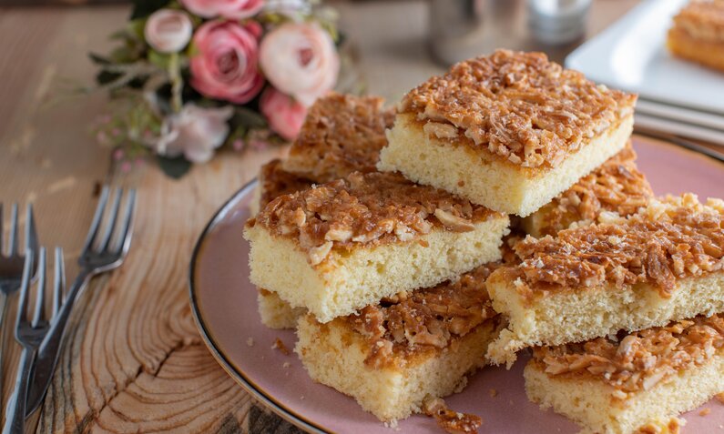 Stücke von Buttermilch-Blechkuchen angerichtet übereinander auf einem weißen Teller. | © Getty Images / Angelika Heine