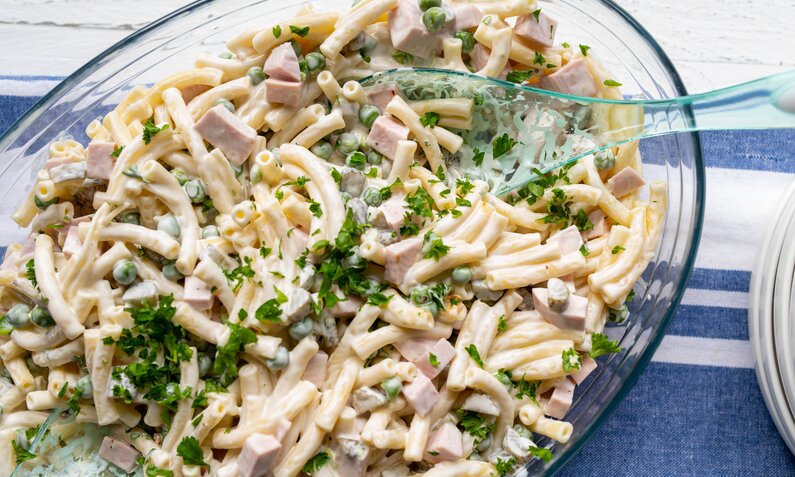 Nudelsalat mit Fleischwurst und Erbsen ohne Mayo aber mit Joghurt in einer Glasschüssel angerichtet. | © Getty Images / Angelika Heine