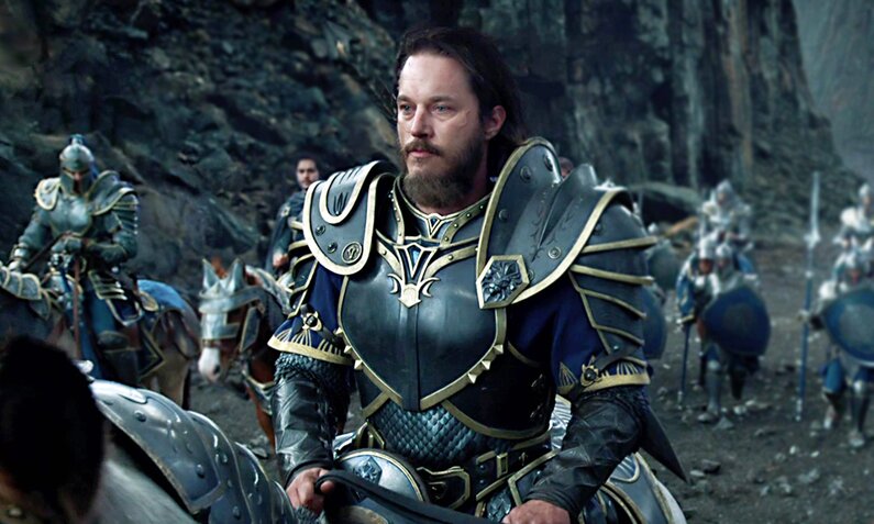 Travis Fimmel reitet als Krieger in Rüstung mit anderen durch eine düstere Schlucht in einer Szene aus dem Fantasy-Kinofilm "Warcraft: The Beginning" | © ddp images/LMKMEDIA