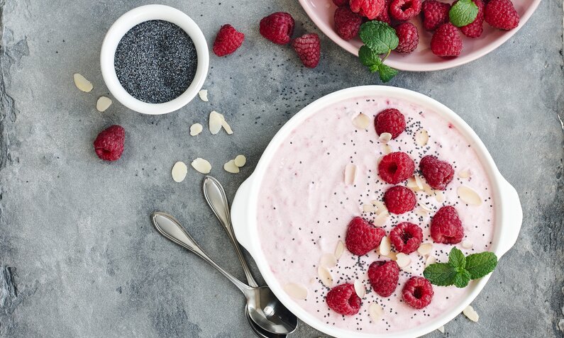 Schüssel mit Himbeerjoghurt und frischen Himbeeren sowie einem frische Minzeblatt. | © Getty Images / Nataliia Sirobaba