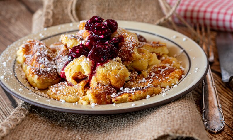 Fluffiger Kaiserschmarrn Low Carb ohne Zucker mit Puderzucker bestreut und mit heißen Kirschen garniert. | © Adobe Stock / Angelika Heine