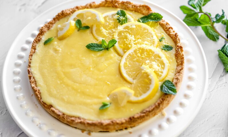 Angeschnittener Kuchen mit Zitronen belegt auf einem weißen Teller. | © Getty Images / lisegagne