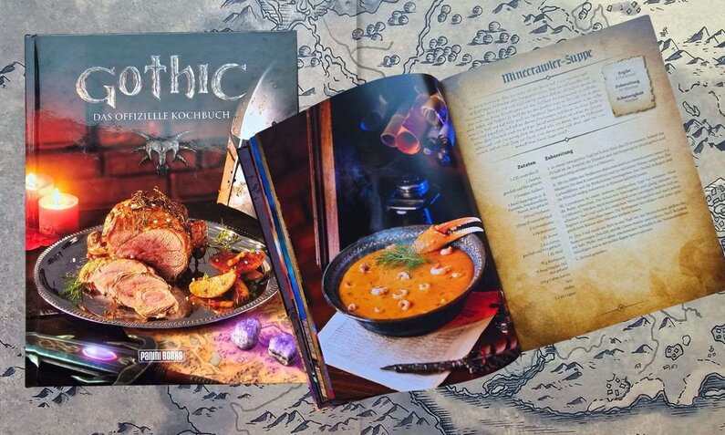 Offizielles "Gothic"-Kochbuch mit rustikaler Fleischplatte und dampfender Krabbensuppe, auf einer Landkarte liegend. | © Sabrina Forst